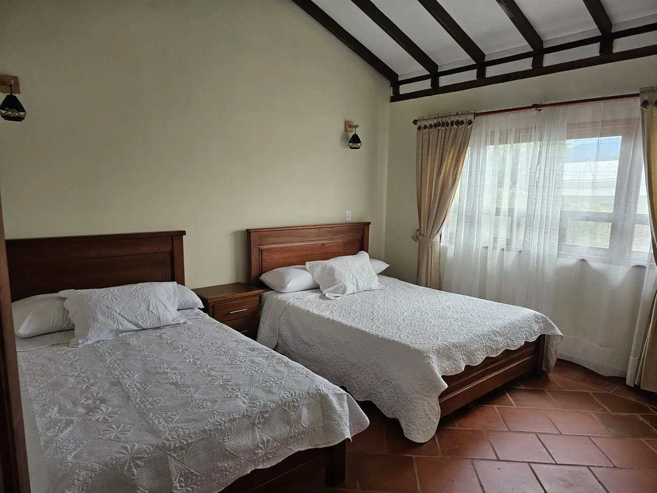 Habitación con cama doble y cama sencilla, techos en madera